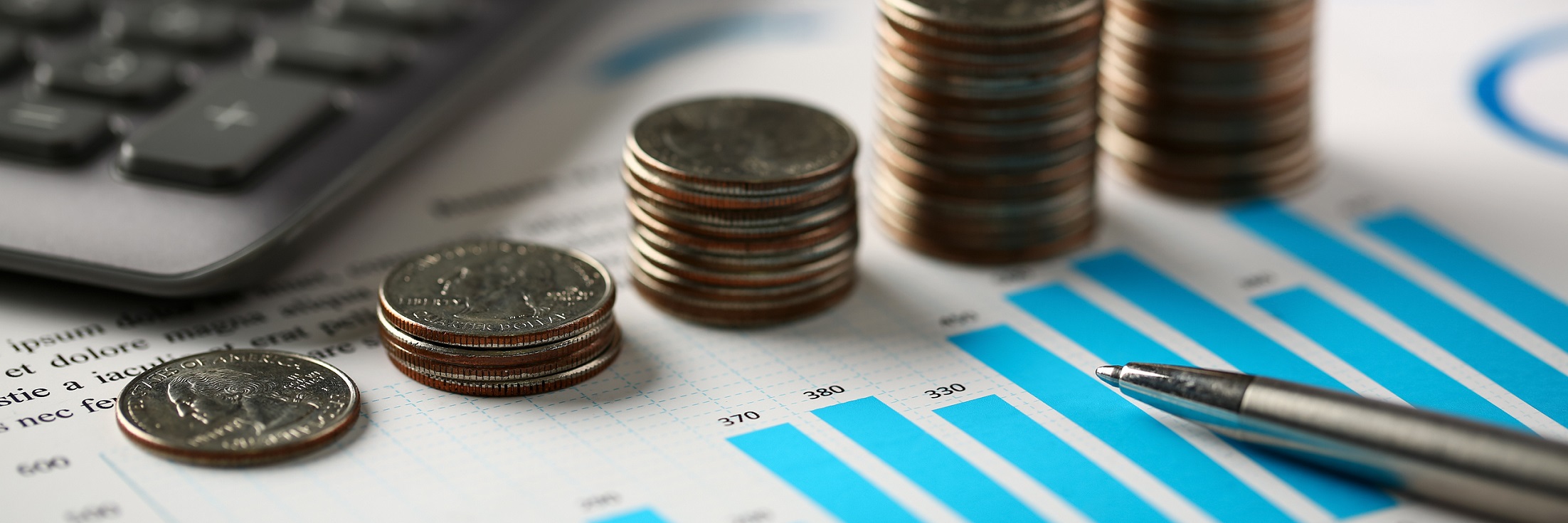 Pile of silver coins stand at financial graph papers